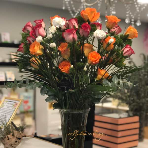 Bouquet of orange and pink roses in a clear glass vase
