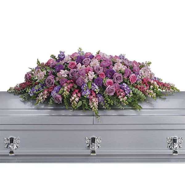 Lavender and pink floral casket spray on a gray casket