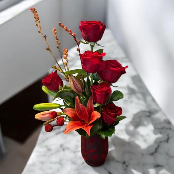 Red roses and orange lilies in a red glass vase