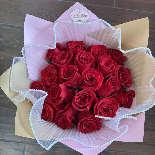 Bouquet of red roses wrapped in pink and beige paper with white tulle