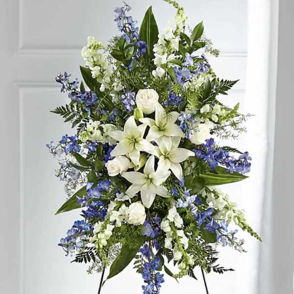 Standing floral spray with white lilies, roses, and blue flowers