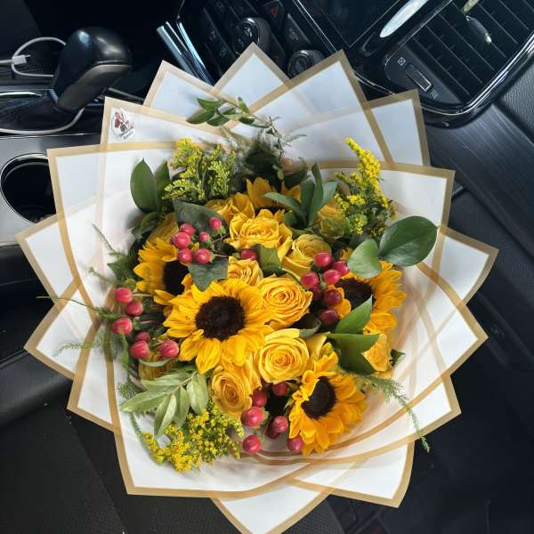 Bouquet of yellow roses and sunflowers wrapped in white paper
