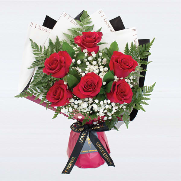 Bouquet of red roses with baby's breath and fern foliage in decorative wrapping