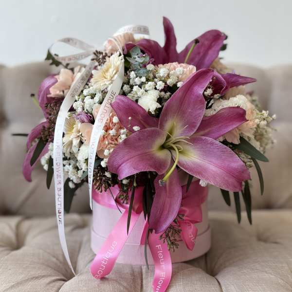Pink lilies and mixed pastel flowers in a round pink box with ribbons