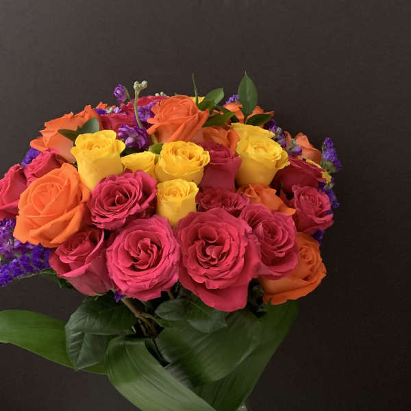 Bouquet of pink, orange, and yellow roses in a clear glass vase