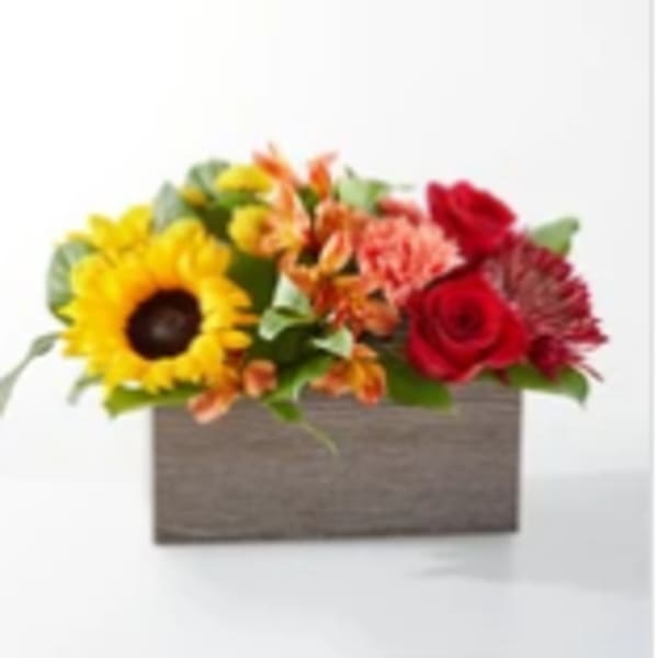 Mixed flower arrangement in a rectangular wooden box with a sunflower and red roses