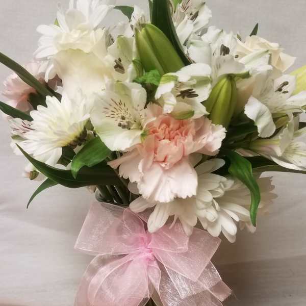 White and pale pink bouquet in a glass vase with a pink ribbon