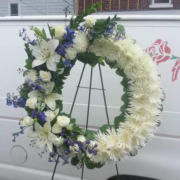 White floral wreath on a standing easel with blue accents