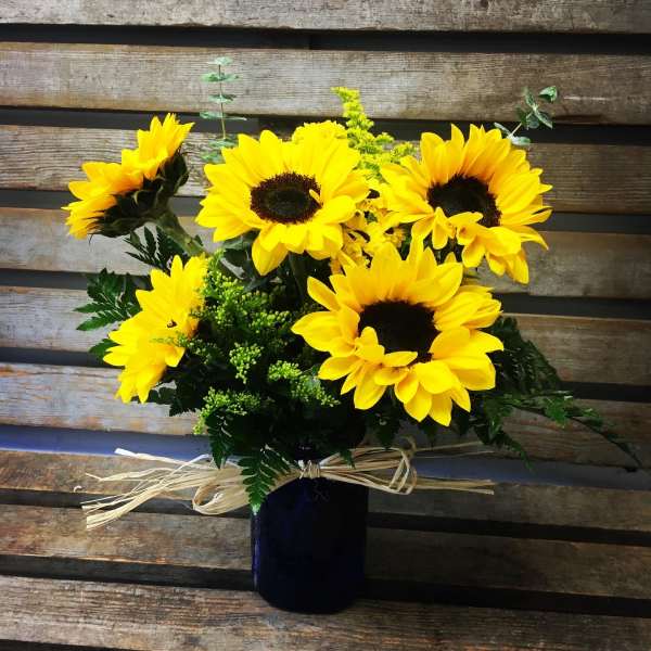 Bouquet of yellow sunflowers in a dark vase