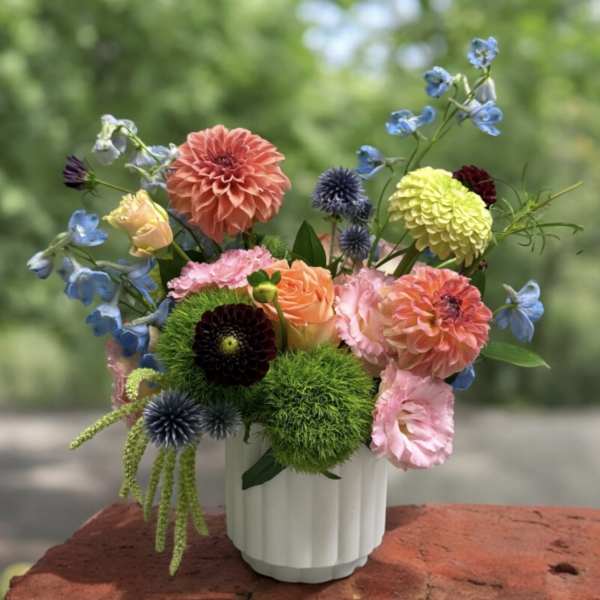 Colorful mixed bouquet in a white vase with dahlias and other blooms