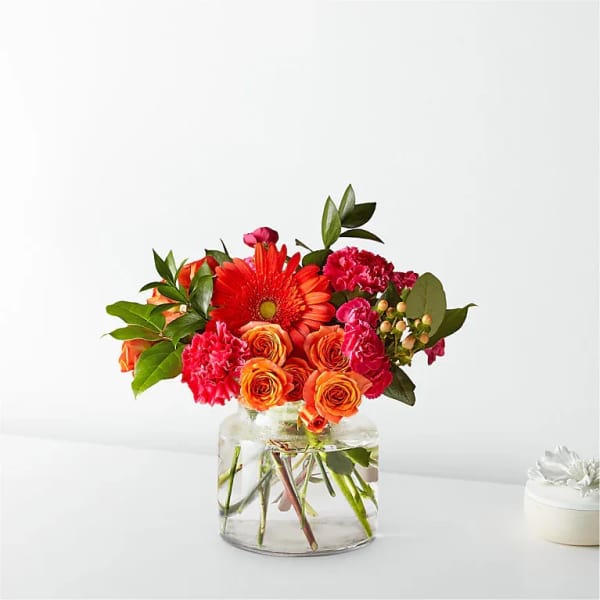 Orange and pink mixed bouquet in a clear glass vase