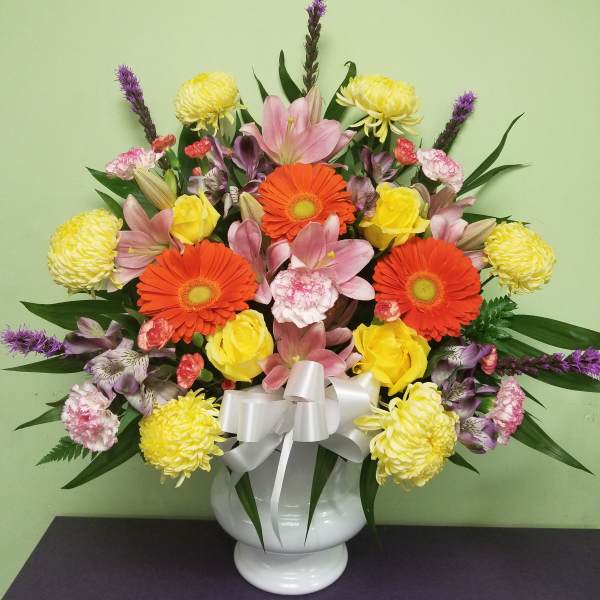 Colorful mixed bouquet in a white vase with a silver bow