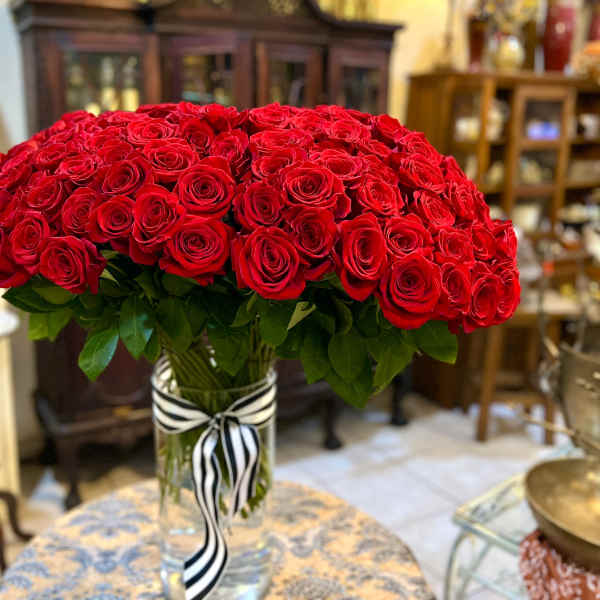 Large bouquet of red roses in a clear glass vase with a striped ribbon