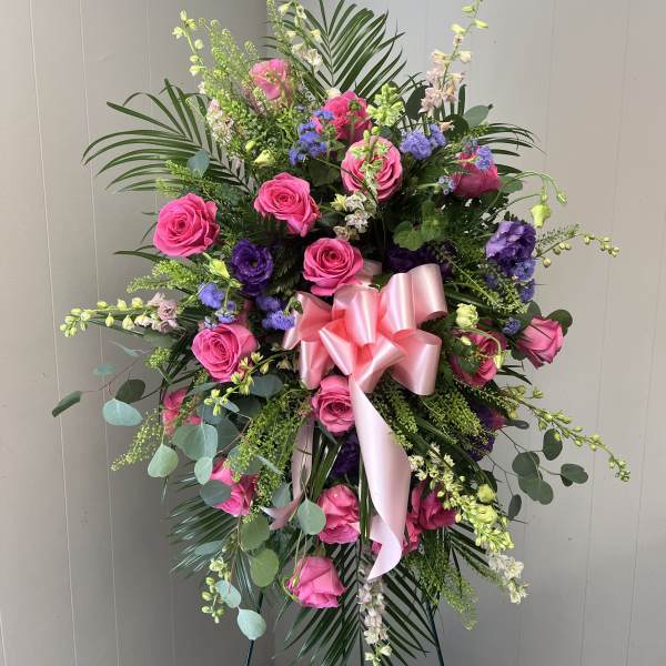 Standing floral spray with pink roses and purple blooms on an easel