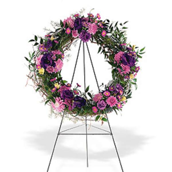 Standing wreath of purple and pink flowers on a metal easel