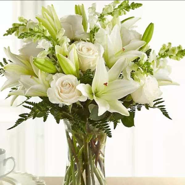 White lilies and roses arranged in a clear glass vase