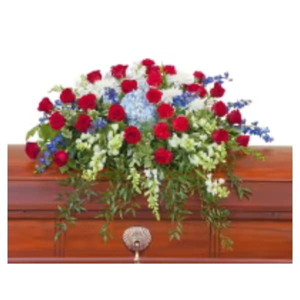 Red roses and white flowers arranged on a wooden casket