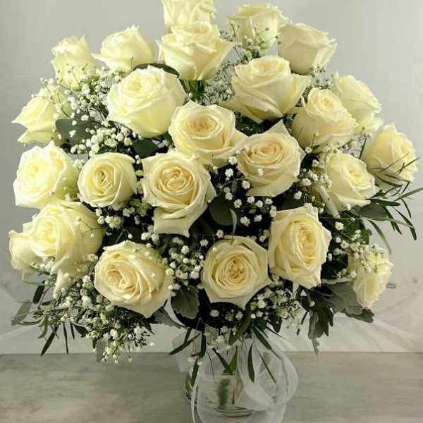 Bouquet of cream roses with baby's breath in a clear glass vase