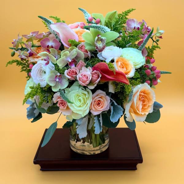 Mixed bouquet of roses, orchids, and calla lilies in a glass vase