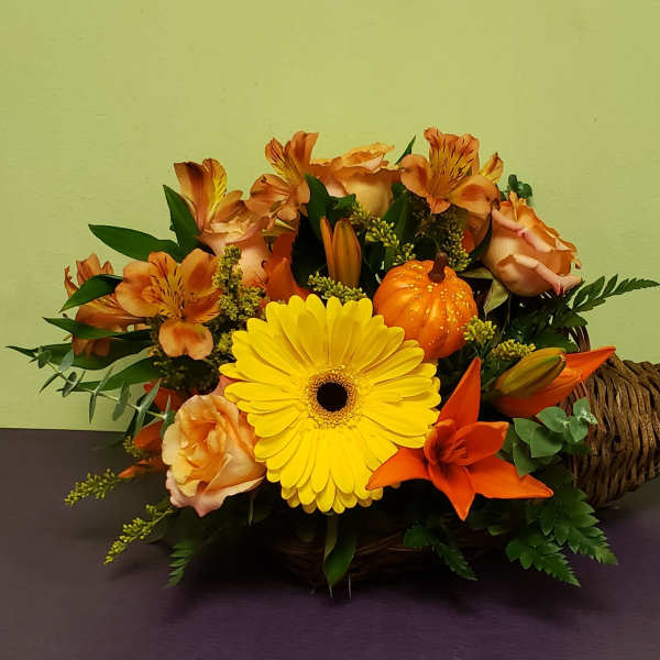 Basket arrangement with yellow gerbera, orange lilies, and peach roses