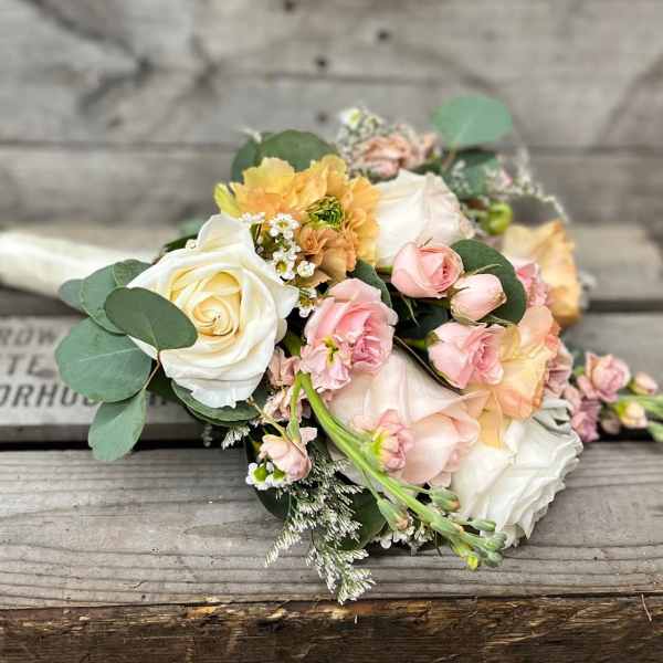 Bouquet of cream and blush roses with peach flowers and greenery