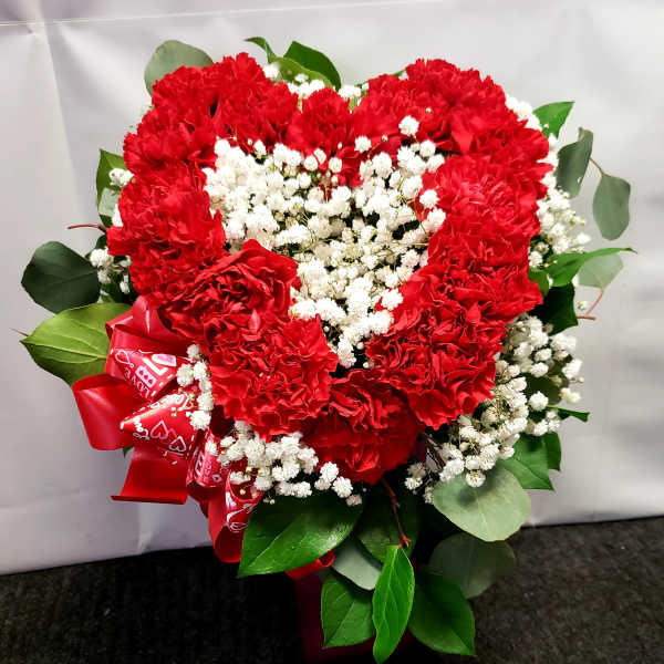 Heart-shaped bouquet of red carnations with white baby's breath and a red ribbon