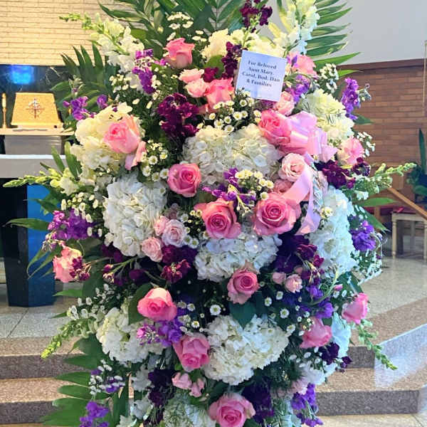 Large standing floral spray with pink roses, white hydrangeas, and purple flowers