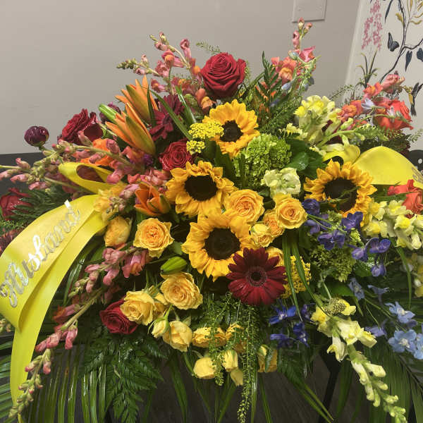 Large mixed flower spray with yellow ribbon and roses, sunflowers, and lilies