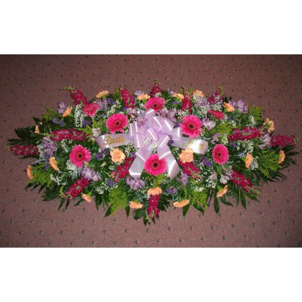 Large floral casket spray with pink gerbera daisies and a lavender ribbon