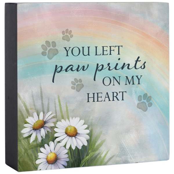 Memorial plaque with daisies and the words "You left paw prints on my heart"