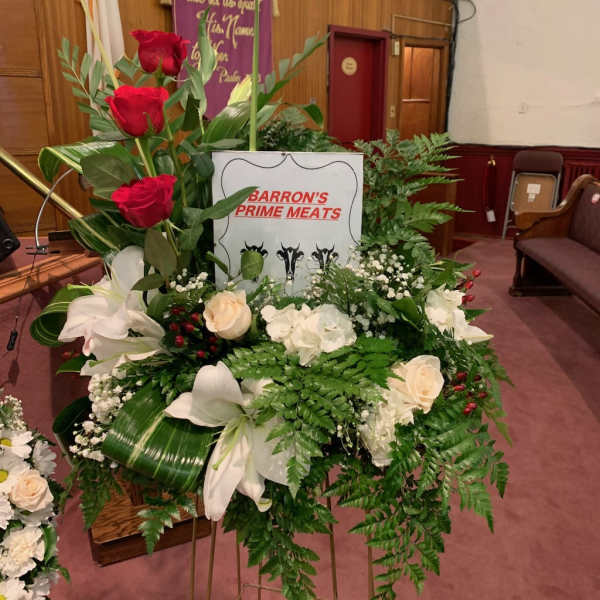 Standing floral tribute with red and white flowers on a metal easel