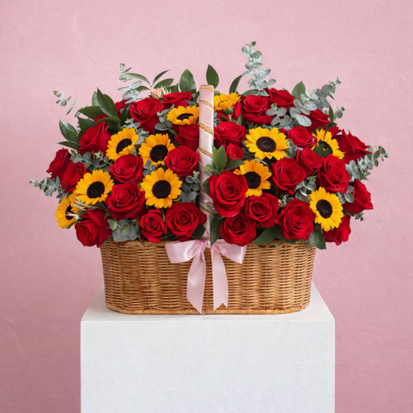 Basket of red roses and yellow sunflowers with a pink ribbon