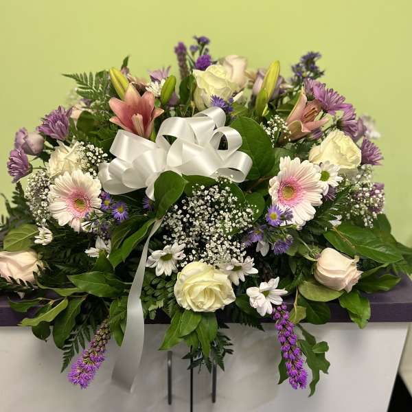 Mixed bouquet with pink lilies, roses, and purple flowers tied with a white ribbon
