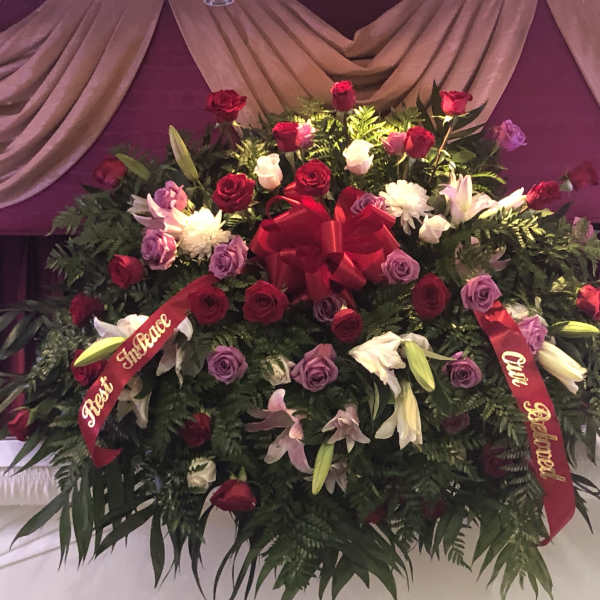 Large floral spray of red, pink, purple, and white flowers with ribbons