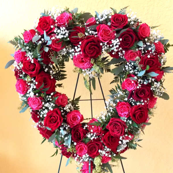 Heart-shaped rose wreath on a stand with red and pink roses