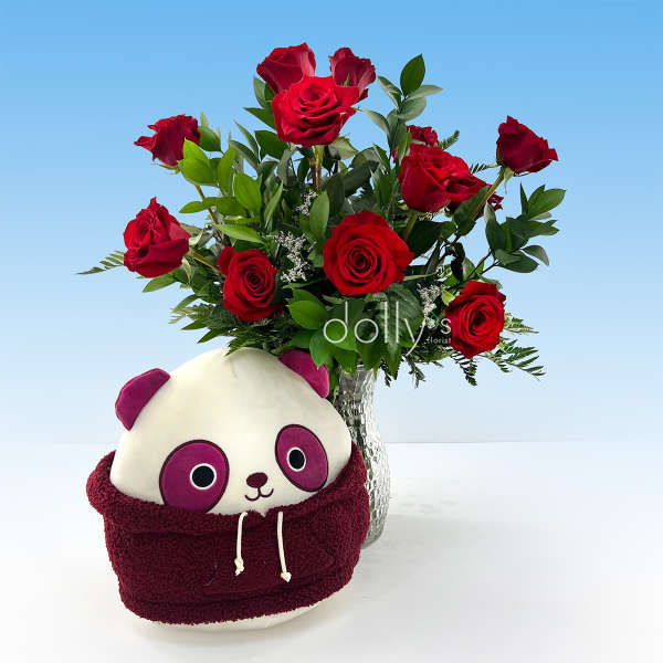 Red roses in a glass vase with a panda plush in front