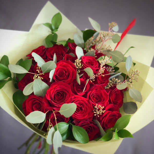 Bouquet of red roses with eucalyptus in pale wrapping