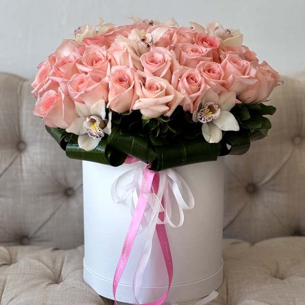 Pink roses and white orchids arranged in a white hat box