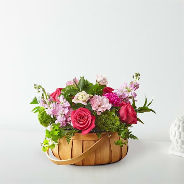 Pink and red roses arranged in a woven basket