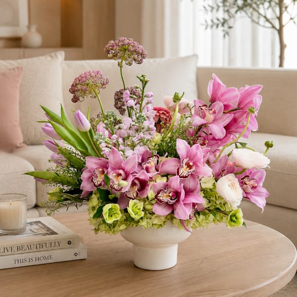 Pink orchid and tulip arrangement in a white vase