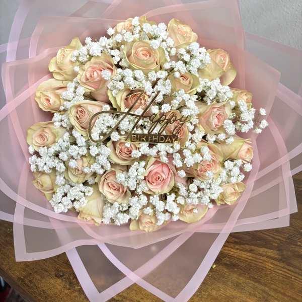 Bouquet of pale pink roses with white baby's breath and a birthday topper