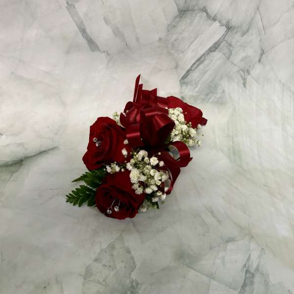 Red rose corsage with white baby's breath and a burgundy ribbon
