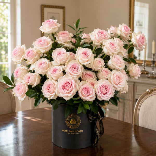 Large arrangement of pale pink roses in a black hatbox