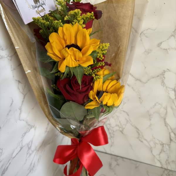 Bouquet of red roses and yellow sunflowers wrapped in brown paper with a red ribbon