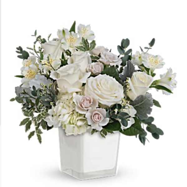 White roses and pale blooms arranged in a clear square vase