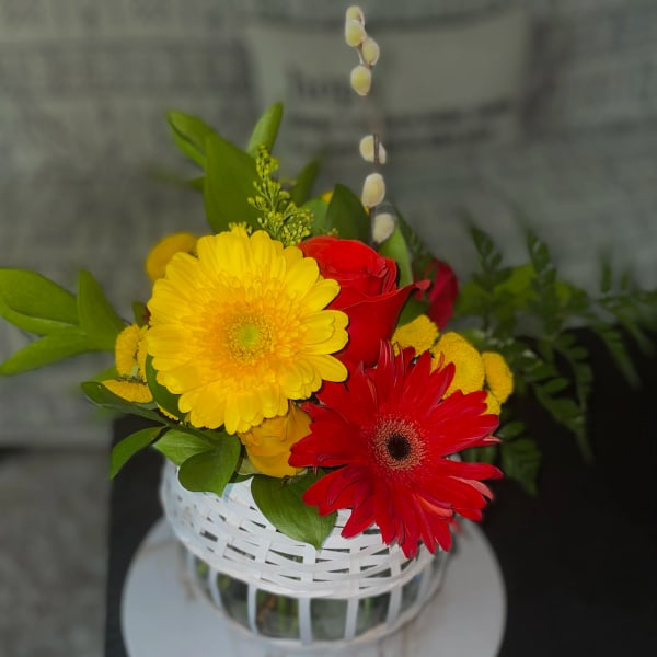 Yellow and red gerbera daisies in a white basket vase