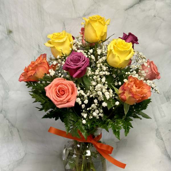 Bouquet of multicolored roses in a glass vase with a ribbon