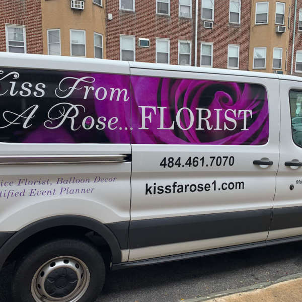 Branded florist van with a purple rose graphic and business text