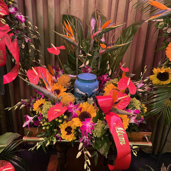 Large tropical floral arrangement with sunflowers, orchids, and an urn centerpiece