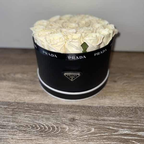 Cream roses arranged in a black round box with Prada branding